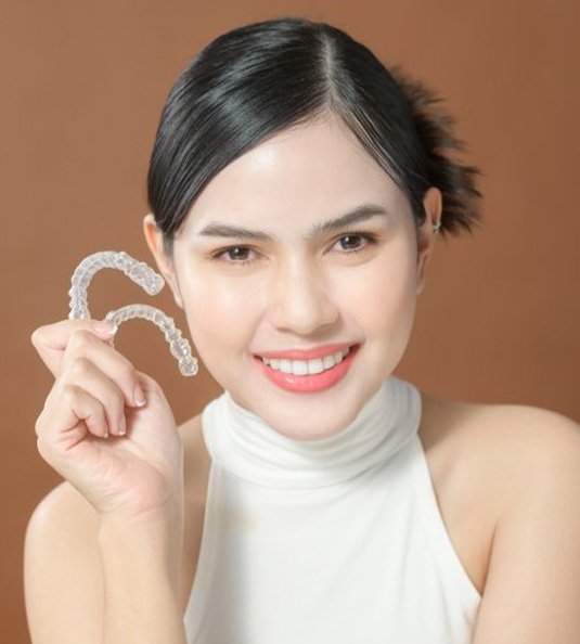 Smiling lady shows off clear aligners