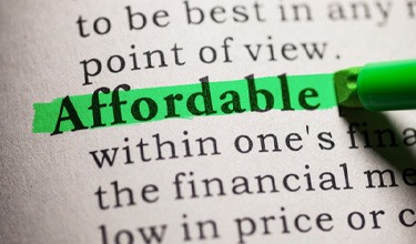 a person highlighting the word “affordable” in a dictionary