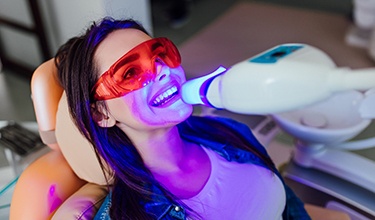 person sitting in a dental chair receiving teeth whitening treatment