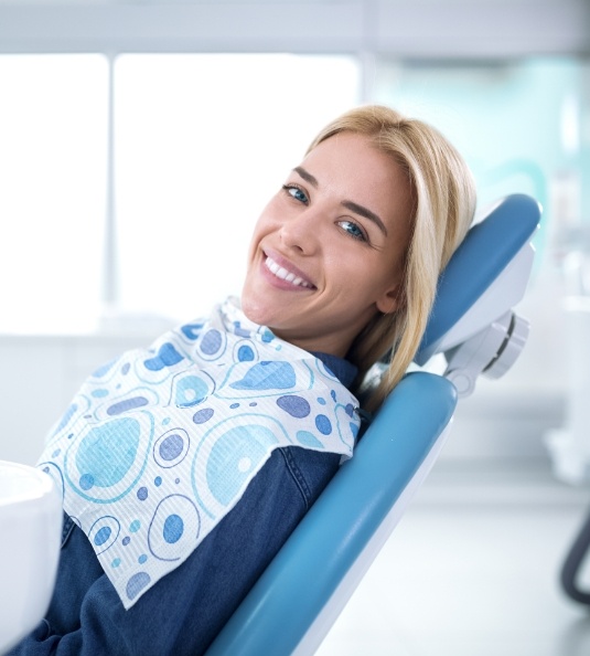 Woman in dental chair looking to side and smiling