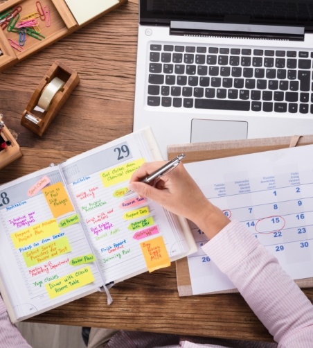 Filling out planner on a busy desk