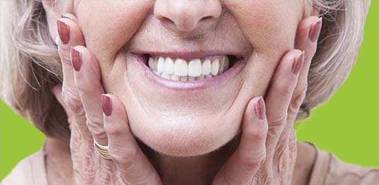 older woman showing clean dentures