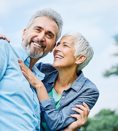 Middle-aged couple smiling after learning how dentures are made in Carrollton
