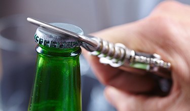 Closeup of patient using bottle opener to prevent dental emergencies in Carrollton 