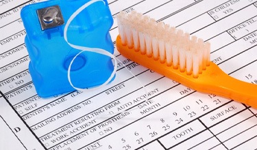 Toothbrush and floss on dental insurance form