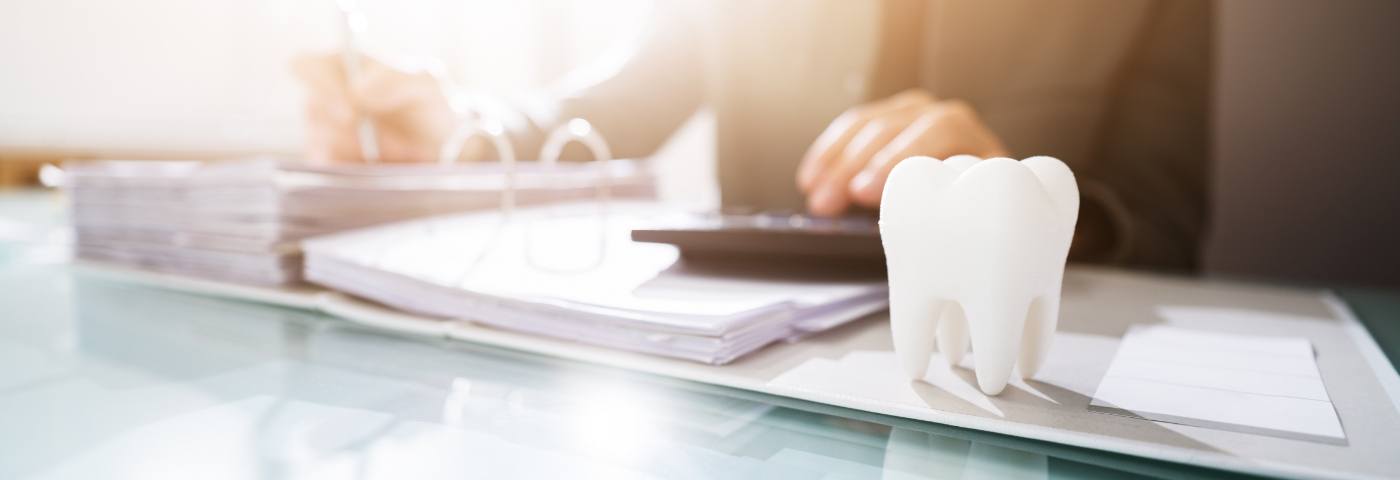 Model tooth in foreground with person using calculator in background