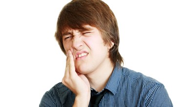 young man holding jaw in pain