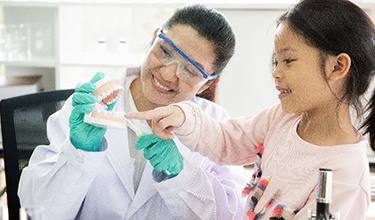 a dental hygienist showing a child a model of a mouth