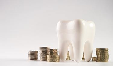A tooth model and coins that symbolize the cost of teeth whitening