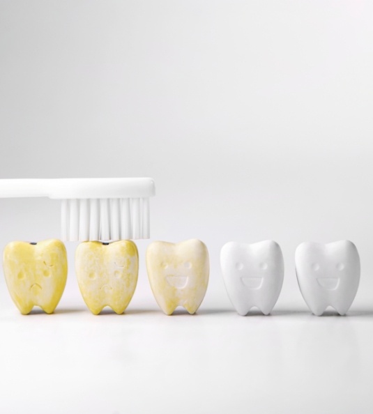 Discolored model teeth being brushed until white