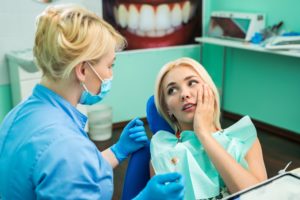 woman in pain sitting in chair at emergency dentist
