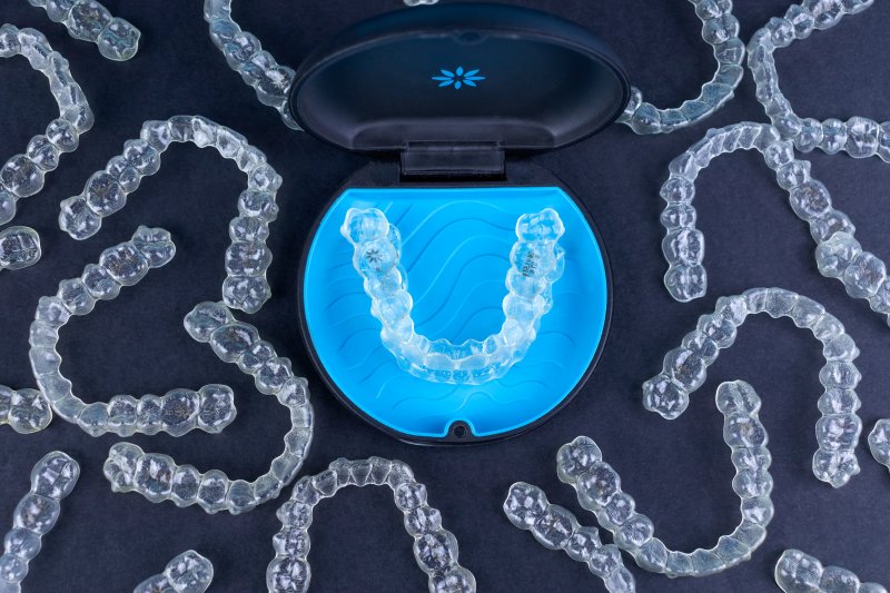Several Invisalign trays set against a dark background