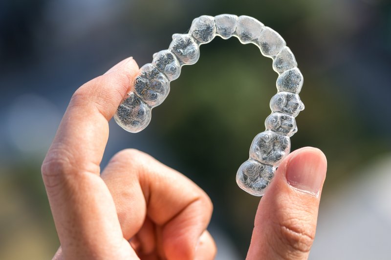 An Invisalign aligner held between two fingers