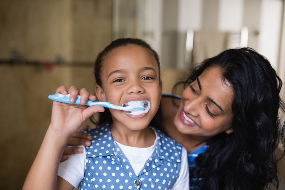 person helping child with autism brush their teeth