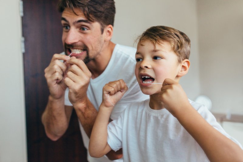 A father teaching his son how to floss