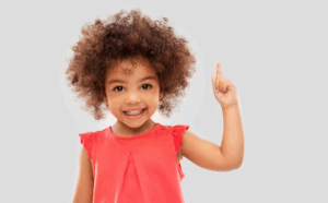 Child smiling and pointing her finger in the air