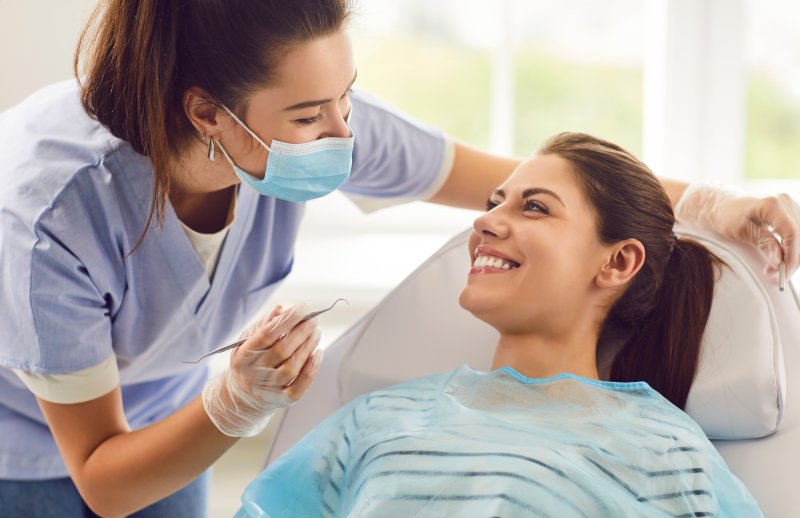 A dental hygienist interacting with a smiling patient