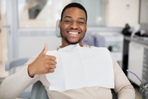 Man holding a thumbs up and smiling at the dentist